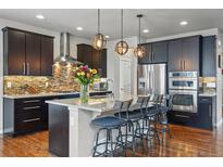 Modern kitchen featuring dark cabinets, stainless steel appliances, granite countertops, and an island with seating at 15275 W La Salle Ave, Lakewood, CO 80228