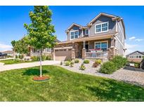 Charming two-story home with stone accents, a manicured lawn, and a welcoming front porch at 23879 E Narrowleaf Pl, Aurora, CO 80016