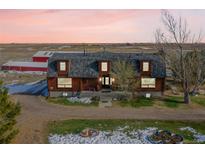 Charming log home with dormer windows and a lush front lawn nestled in a serene rural setting at 48155 E 56Th Ave, Bennett, CO 80102