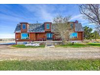Charming log home featuring a covered porch, dormer windows, and inviting curb appeal at 48155 E 56Th Ave, Bennett, CO 80102