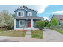 Charming blue two-story home with a welcoming red door, white porch columns, and a well-manicured lawn at 3186 Springmeadow Cir, Castle Rock, CO 80109