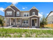 Charming townhome featuring a covered front porch, manicured lawn and neutral two-tone color scheme at 14096 Red Cosmos St, Parker, CO 80134