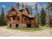 Charming log cabin with a stone foundation, wooden decks, and surrounded by tall pine trees at 5724 Highway 9, Breckenridge, CO 80424