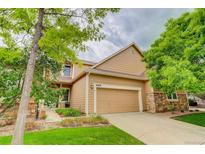 Charming two-story home featuring a manicured lawn, stone accents, and an attached two-car garage at 6068 W Utah Ln, Lakewood, CO 80232