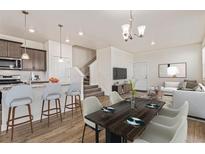 Stylish open-concept living area with a dining table, island seating, and easy access to the staircase at 21821 E 7Th Ave, Aurora, CO 80018
