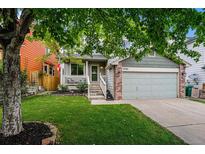 Charming home with a well-maintained lawn, tree, and covered front porch at 12261 N Holly Way, Brighton, CO 80602