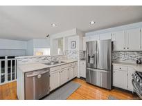 Modern kitchen featuring stainless steel appliances, white cabinetry, and stylish backsplash, perfect for culinary enthusiasts at 12261 N Holly Way, Brighton, CO 80602