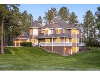 Beautiful multi-story home featuring a turret, covered porch, and lush green lawn at 407 S White Tail Dr, Franktown, CO 80116