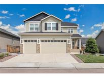 Home featuring a three-car garage, stone accents, and a well-manicured lawn at 6401 Leilani Ln, Castle Rock, CO 80108