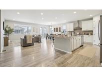 Bright, open-concept living space features wood floors and seamless flow into the modern kitchen and dining area at 617 Iris St, Brighton, CO 80601