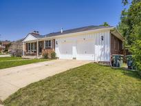 Charming home with a two-car garage, brick accents, and a well-manicured lawn on a sunny day at 10736 Logan Ct, Northglenn, CO 80233