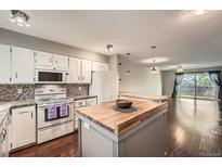 Bright kitchen featuring white cabinets, butcher block island, and stainless steel appliances at 6492 Simms St # A, Arvada, CO 80004