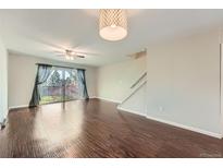 Bright living room boasts hardwood floors, a ceiling fan, and sliding doors to the backyard at 6492 Simms St # A, Arvada, CO 80004