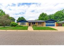 Charming brick home boasts a well-manicured lawn, blue trim, and an attached two car garage at 353 S Niagara St, Denver, CO 80224