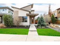 Modern home with unique architecture, fresh green lawn, and pathway to the bright orange front door at 1848 W 68Th Ave, Denver, CO 80221