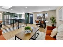 Open-concept living space with modern decor, wood floors, and natural light from large windows at 10431 Holland St, Broomfield, CO 80021