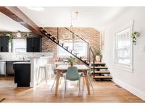 Bright dining room features brick wall, modern light fixture, floating stairs and wood floors at 4452 Stuart St, Denver, CO 80212