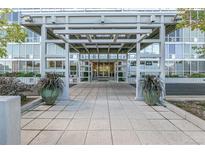 Inviting building entrance with tiled walkway, large potted plants, and a modern canopy at 3100 E Cherry Creek South Dr # 303, Denver, CO 80209