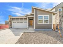 Charming gray home features a stone accent, two-car garage, and a welcoming front entrance at 9283 Biscay St, Commerce City, CO 80022