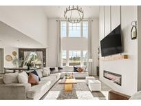 Bright living room boasts large windows, fireplace, modern chandelier, and neutral decor at 840 Avena Dr, Elizabeth, CO 80107