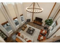 Stunning living room with soaring ceilings, a modern chandelier, and an elegant fireplace at 9266 E 35Th Ave, Denver, CO 80238