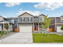 Charming two-story home features a covered porch, well-maintained lawn, and an attached two-car garage at 715 N Amory St, Watkins, CO 80137
