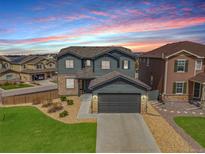 Charming two-story home with a gray exterior, stone accents, manicured lawn, and a two-car garage at 880 Mcmurdo Cir, Castle Rock, CO 80108