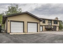 Spacious home exterior shows a two-car garage with attached home and long driveway at 30839 Manitoba Dr, Evergreen, CO 80439