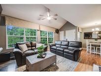 Inviting living room featuring hardwood floors, vaulted ceilings, and large windows with views of lush greenery at 8337 S Upham Way # 103, Littleton, CO 80128