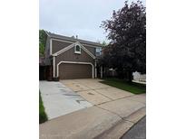 Two-story home with a two car garage and neutral siding, complemented by mature landscaping and a concrete driveway at 573 Entrada Dr, Golden, CO 80401