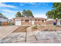 Charming brick home featuring a landscaped front yard with a walkway and freshly planted flower beds at 11976 E Arizona Dr, Aurora, CO 80012