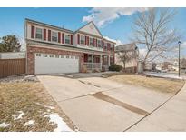 Two-story home with brick facade, white garage door, red shutters, front porch and a concrete driveway at 9451 S Hackberry Ln, Highlands Ranch, CO 80129