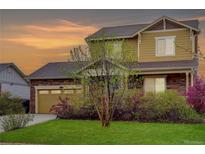 Charming two-story home with brick and siding, complemented by a well-manicured lawn and vibrant foliage at 25812 E Cedar Pl, Aurora, CO 80018