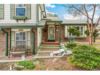 Charming front entrance with brick accents, green trim, and a welcoming doorway and landscaped front yard at 7681 S Jellison St, Littleton, CO 80127
