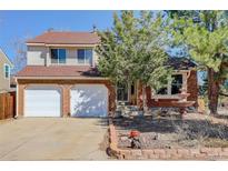 Charming two-story home with a brick facade, two-car garage, mature trees, and manicured landscaping at 15099 E Wagontrail Pl, Aurora, CO 80015