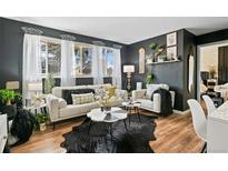 Inviting living room featuring dark walls, wood floors, and bright natural light from the large windows at 10211 Ura Ln # 10-105, Thornton, CO 80260