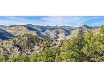 Scenic mountain view with lush evergreen trees and snow-capped peaks on a sunny day at 2433 Dogie Spur, Golden, CO 80403