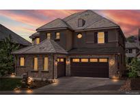 Beautiful home exterior with stone accents, brown siding, and a tiled roof at dusk at 6878 Northstar Ct, Castle Rock, CO 80108