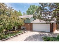 Charming two-story home featuring a brick facade, well-manicured lawn, and an attached two-car garage at 7046 W 62Nd Pl, Arvada, CO 80003