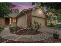 Charming home exterior features a two-car garage with stone accents and landscaped yard at 7582 S Newport Ct, Centennial, CO 80112