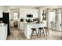 Modern kitchen featuring white cabinetry, stainless steel appliances, an island with stools, and hardwood flooring at 39733 Penn Rd, Elizabeth, CO 80107
