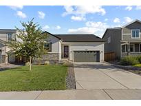 Charming single-story home with a manicured lawn, stone accents, and a two-car attached garage at 27491 E 10Th Dr, Aurora, CO 80018