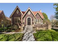 Charming brick home with a red-tiled roof and landscaped front yard in a neighborhood setting at 2591 Albion St, Denver, CO 80207