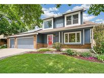 Charming two-story home with a well-manicured lawn, brick accents, and colorful flower beds at 13701 Yank Way, Arvada, CO 80004