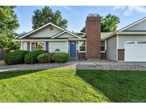 Charming single-story home with a manicured lawn, brick chimney and a welcoming blue front door at 5193 S Flanders Ln, Centennial, CO 80015