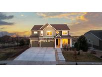 Inviting two-story home featuring a three-car garage, manicured lawn, and charming front porch at 27596 E Jamison Cir, Aurora, CO 80016
