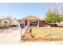 Charming single-story brick home featuring a covered porch and well-maintained front yard with chain link fence at 7971 Quince St, Commerce City, CO 80022
