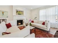 Bright living room with fireplace, white sofas with accent pillows and stylish area rug at 2034 Dahlia St # 1, Denver, CO 80207