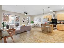Bright living room with wood floors, comfortable seating, and an open floorplan flowing into the kitchen and dining area at 1440 Little Raven St # 110, Denver, CO 80202