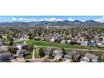 Expansive aerial view showcases a neighborhood surrounded by lush greenery and mountains in the background at 11191 W Crestline Dr, Littleton, CO 80127